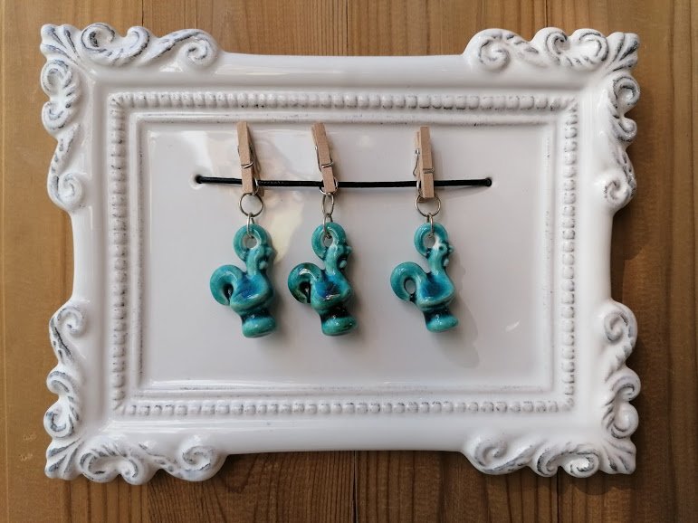 Frame with turquoise roosters on pegs