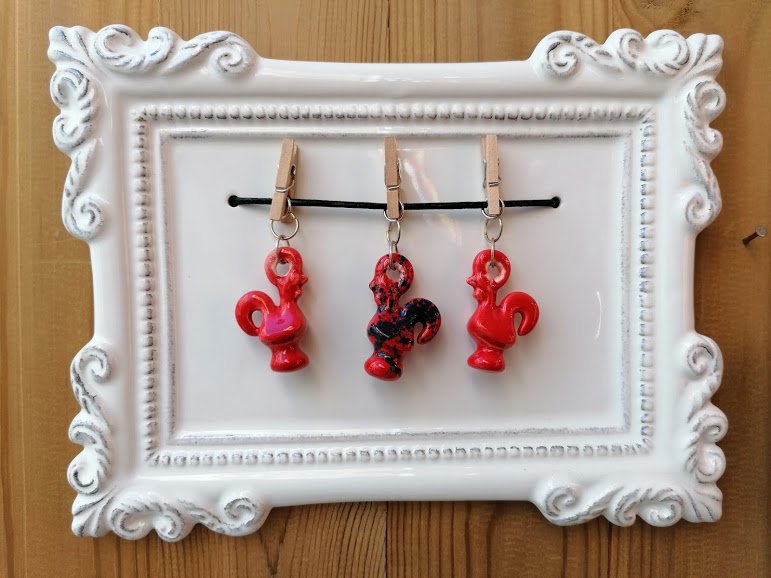 Frame with red and black roosters on pegs